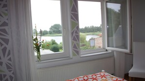 A room with a bed, a window with a view of a lake, and a radiator. - Apartment 'Fewo Schwan' with Shared Terrace, Shared Garden and Wi-Fi (Röbel)
