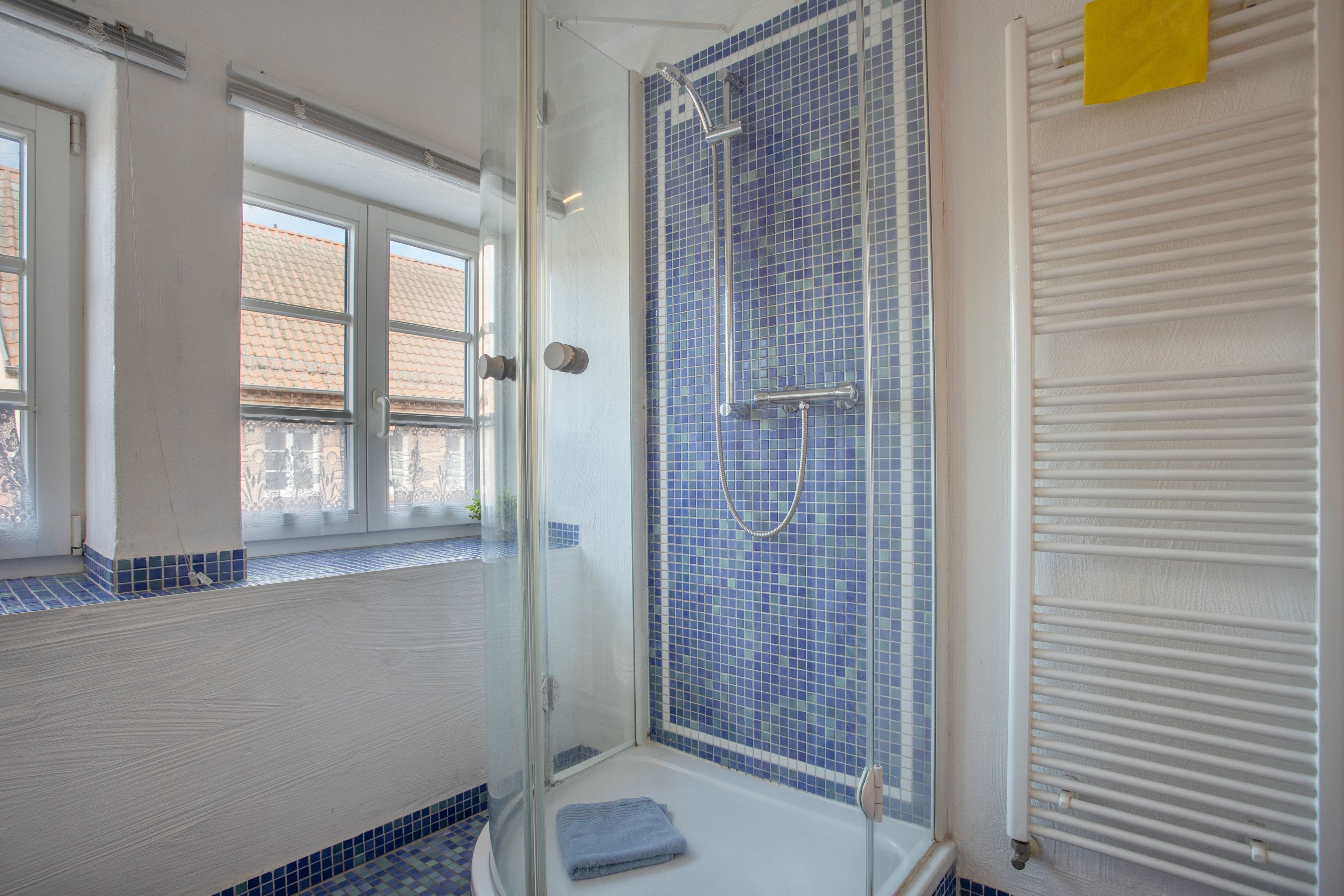 Ein Badezimmer mit Duschkabine, Badewanne und Fenster.