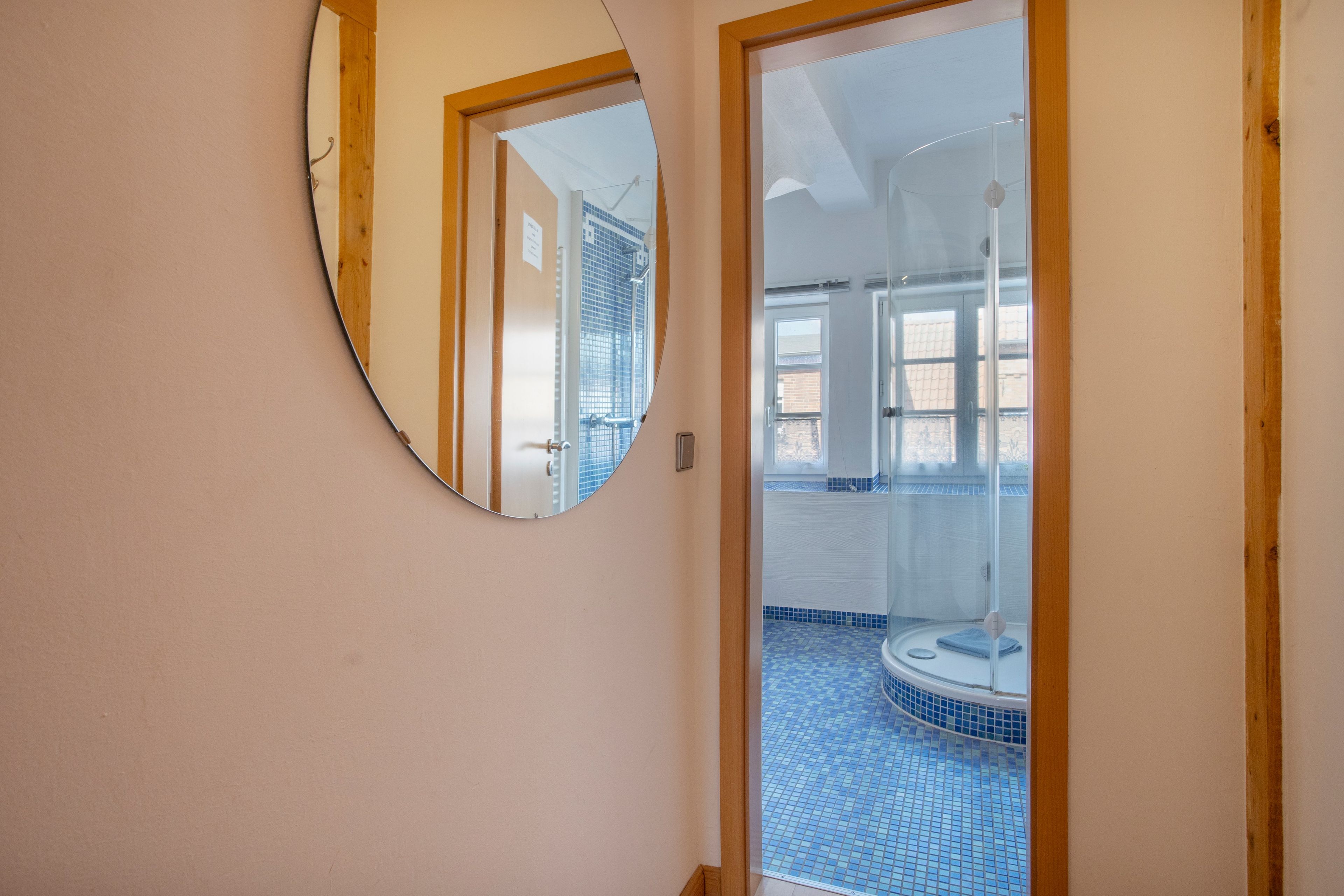 Ein Badezimmer mit Dusche, gefliestem Boden und einem Spiegel an der Wand.