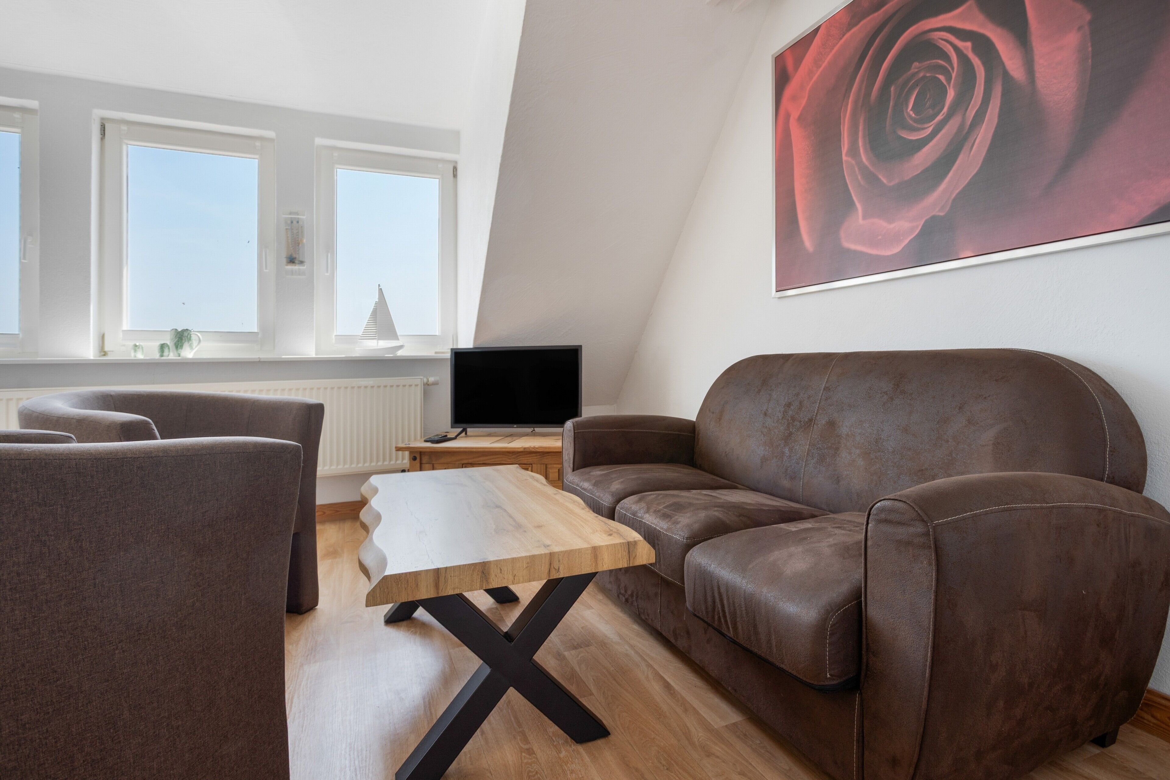 A modern living room with a brown leather sofa, a wooden coffee table, and a large window.