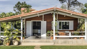 Une maison avec un porche abrité, un téléviseur dans l’espace de divertissement et un chien assis à l’extérieur.