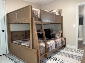 A bunk bed with a ladder, patterned bedding, and a patterned rug.