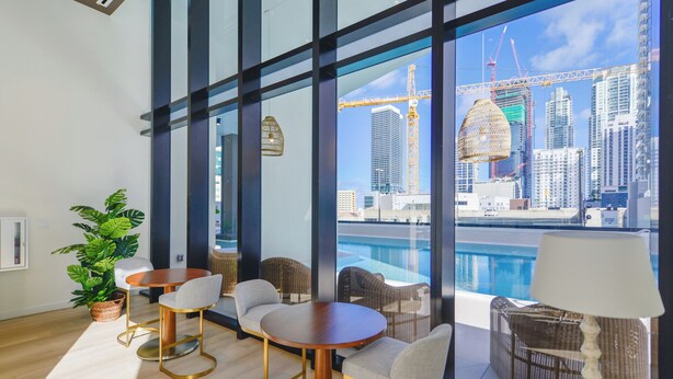Habitación de hotel moderna con ventanas amplias, piscina y vistas a la ciudad.