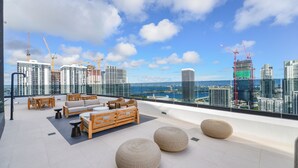 Terraza en la azotea con mobiliario, vista del horizonte urbano y grúas de construcción.