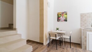 Una scala conduce a una stanza con zona pranzo, un quadro appeso al muro e rivestimento in piastrelle.