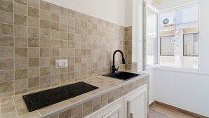 Una cucina con piastrelle beige, un lavandino nero e una finestra con vista sull'esterno.