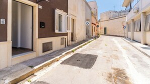 Una stretta via fiancheggiata da edifici, un coperchio di pozzetto e un cielo sereno.