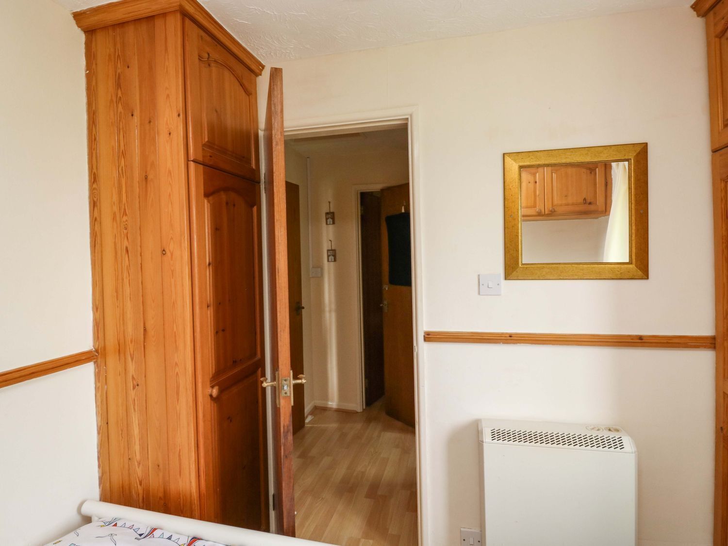 A hallway with wooden doors, a white radiator, and a mirror on the wall.