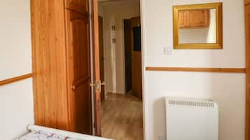 A hallway with wooden doors, a white radiator, and a mirror on the wall.