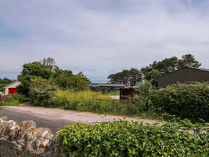 Ländliche Szenerie mit einem Schotterweg, einem roten Gebäude und einem großen Schuppen.