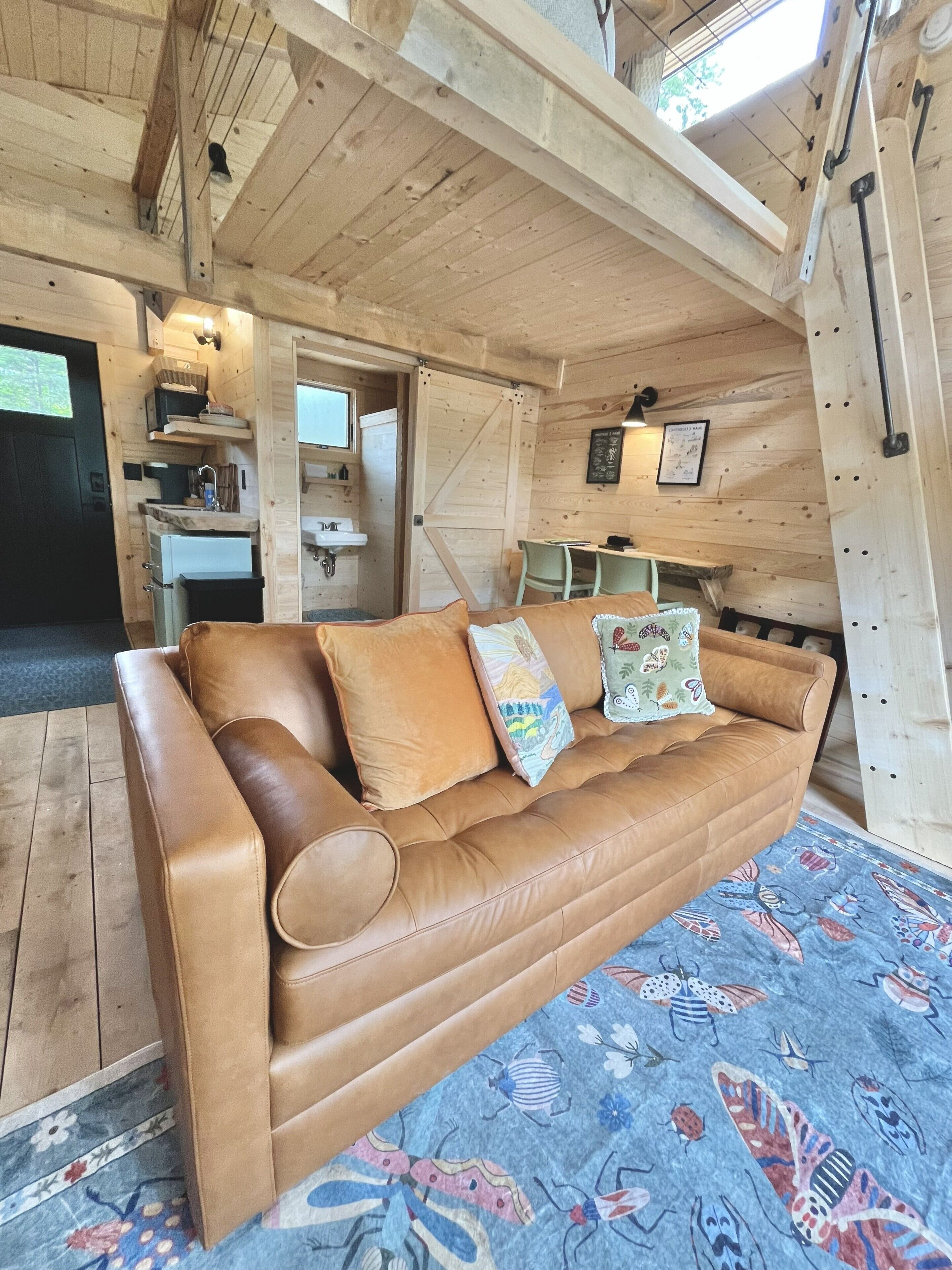 A wooden interior with a leather sofa, a dining table, and a kitchen area.