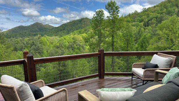 A deck with wicker furniture and a view of a forested hillside. - Awesome 3-bedroom house with AC in charming Burnsville (Burnsville)