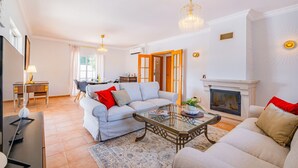 A living room with a sofa, a coffee table, a fireplace, and a dining area with a table and chairs.
