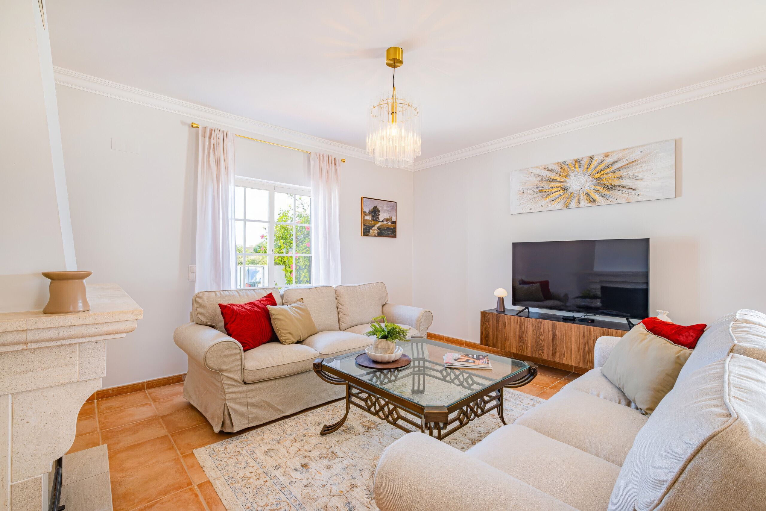 Ein Wohnzimmer mit einer Couch, einem Couchtisch, einem Fernseher und einem Gemälde an der Wand.