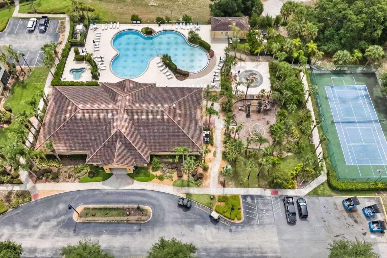 Un grand bâtiment doté d’une piscine, de courts de tennis et d’un parking.