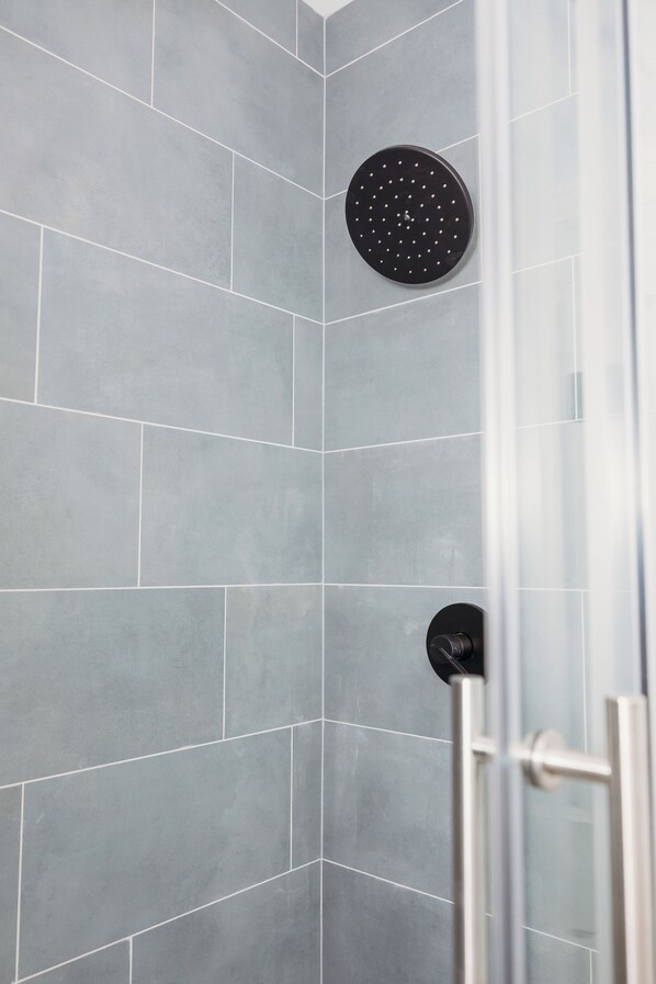 Area doccia con piastrelle grigie e soffione circolare.