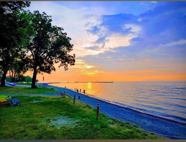 A coastal scene with a grassy area, a walking path, and a body of water. - Luxury Retreat for Discerning Couples and Business Travelers (Vermilion)