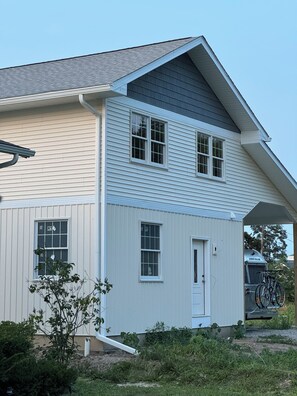 Une maison à deux étages avec un porche à l’avant, un garage et un vélo garé à l’extérieur.