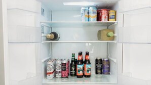 Frigorifero aperto con diversi ripiani contenenti bevande varie e una bottiglia di champagne.