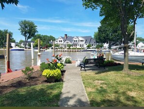 A waterfront property with a dock, a pathway leading to a bench, and a large house with a dock in the background. - Luxury Retreat for Discerning Couples and Business Travelers (Vermilion)