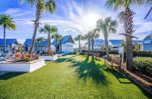 A resort with a well-maintained lawn, palm trees, and a row of blue-roofed buildings. - Stay Anchored at 30a (Watersound)