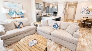 A living room with a sectional sofa, a coffee table, and a dining area with a wooden table and chairs.