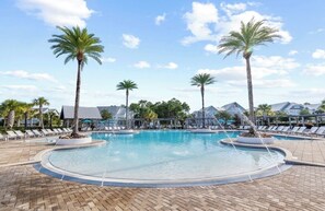 A pool area with lounge chairs and palm trees.