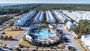 A resort with multiple white buildings, a central swimming pool, and a well-maintained landscape. - Stay Anchored at 30a (Watersound)