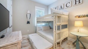 A bunk bed room with a desk, a lamp, and a wall with the word 'BEACH' spelled out. - Stay Anchored at 30a (Watersound)