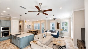 A spacious living area with a kitchen, dining space, and a seating area with a sofa and coffee table. - Stay Anchored 30A | 6-Seat LSV + Heated Pool (Watersound)