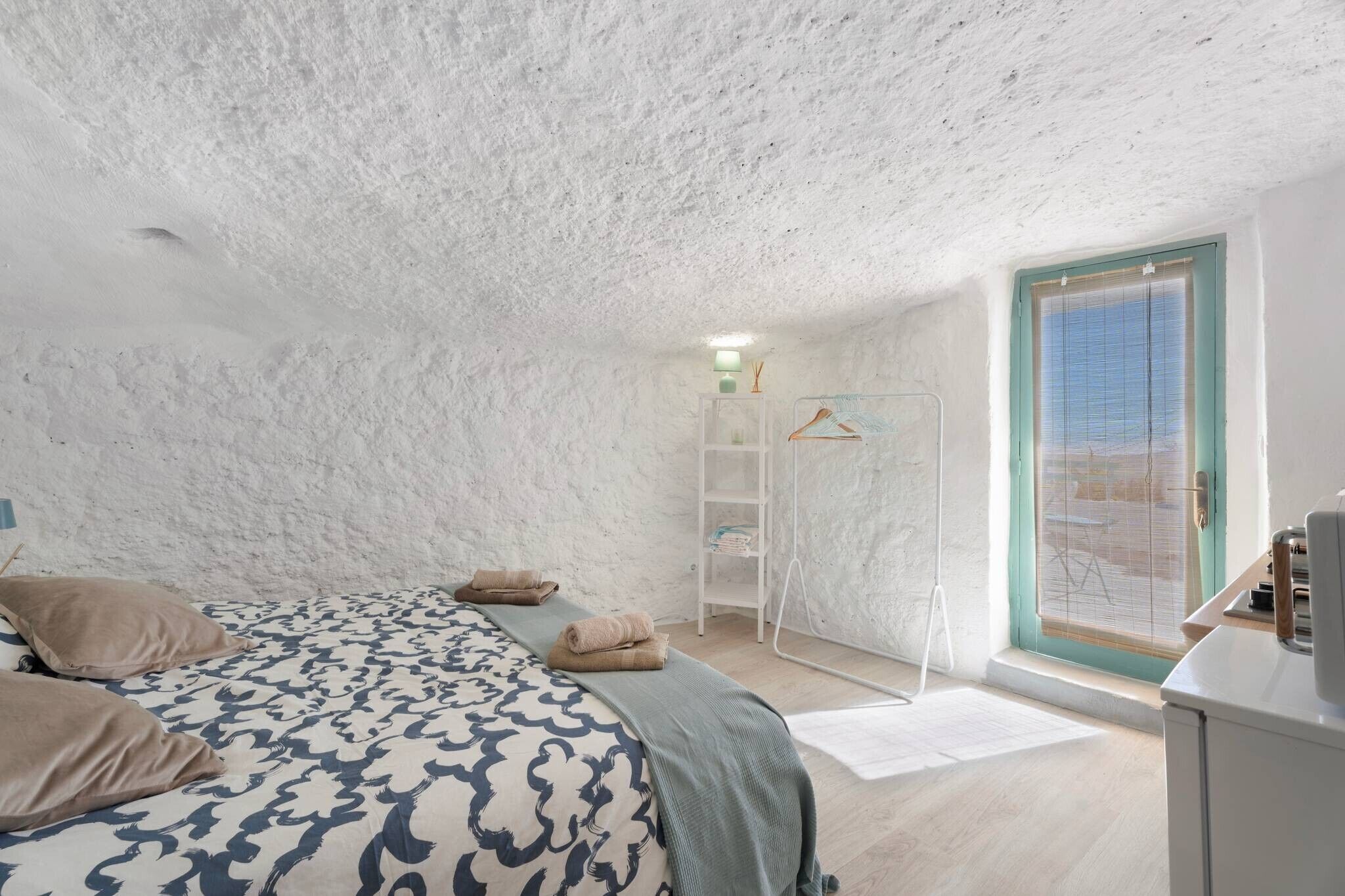 Un dormitorio con cama, armario, ventana y puerta.