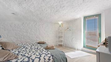 Un dormitorio con cama, armario, ventana y puerta.