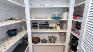 Un garde-manger de cuisine avec des étagères contenant divers ustensiles de cuisine, notamment des casseroles, des poêles et des récipients de rangement.