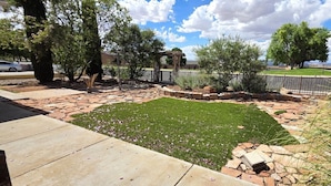 A landscaped backyard with a stone pathway, a grassy area, and a wooden pergola.