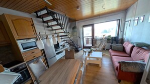 Eine moderne Küche mit einer Holztreppe, einem Essbereich mit einem Holztisch und einem roten Sofa.