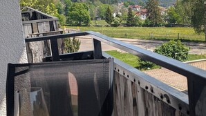 Ein Balkon mit Blick auf einen Weinberg und entfernte Häuser.
