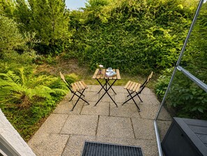 An outdoor patio with a table and chairs, surrounded by dense greenery. - "Waldblick" Vacation Rental with a Balcony and Rooftop Terrace Offering a Stunning South-Facing View - My SWH (Schonach im Schwarzwald)