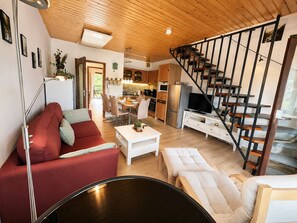 Et moderne opholdsrum med en rød sofa, et hvidt sofabord, et fjernsyn og en trappe.