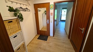 Ein Korridor mit Holztür, Spiegel, einer hängenden Pflanze und einem an der Wand befestigten Ablage.