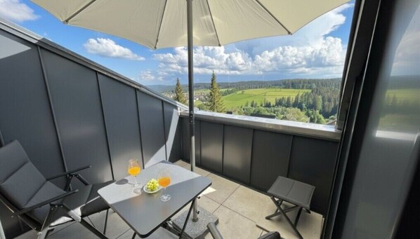 A balcony with a table, chairs, and a table umbrella.