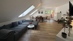 Un loft moderno con comedor, sofá y una mesita con un jarrón de flores.