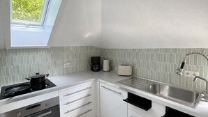 Una cocina moderna con tragaluz, electrodomésticos de acero inoxidable y salpicadero de azulejos.