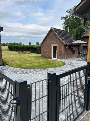 A brick building with a door, a paved patio, and a metal gate.