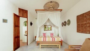 Een slaapkamer met een bed, een bankje, een sofa, een deur en een muur met decoratieve objecten.