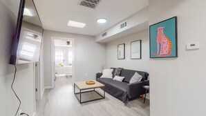 A modern living room with a grey sofa, a coffee table, and a TV mounted on the wall. - ⟫ Dog Run & Courtyard 2 Bedroom Apt w/King Bed W&D (Albuquerque)