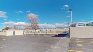 Un estacionamiento con espacios delimitados, un edificio con un cartel con el número '720', y un cielo despejado.