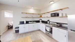 Una cocina moderna con armarios blancos, encimera negra y estufa de acero inoxidable.
