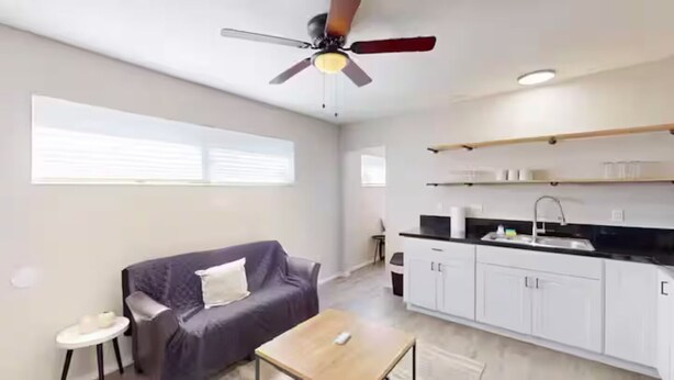 Una sala moderna con un sofá, una mesita y un ventilador de techo.