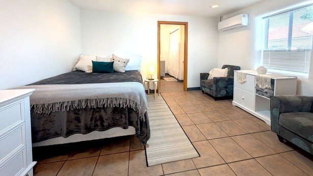 A bedroom with a bed, a desk, a chair, a wardrobe, and a window. - Downtown District Modern Apt - Yard - WiFi - King (Albuquerque)