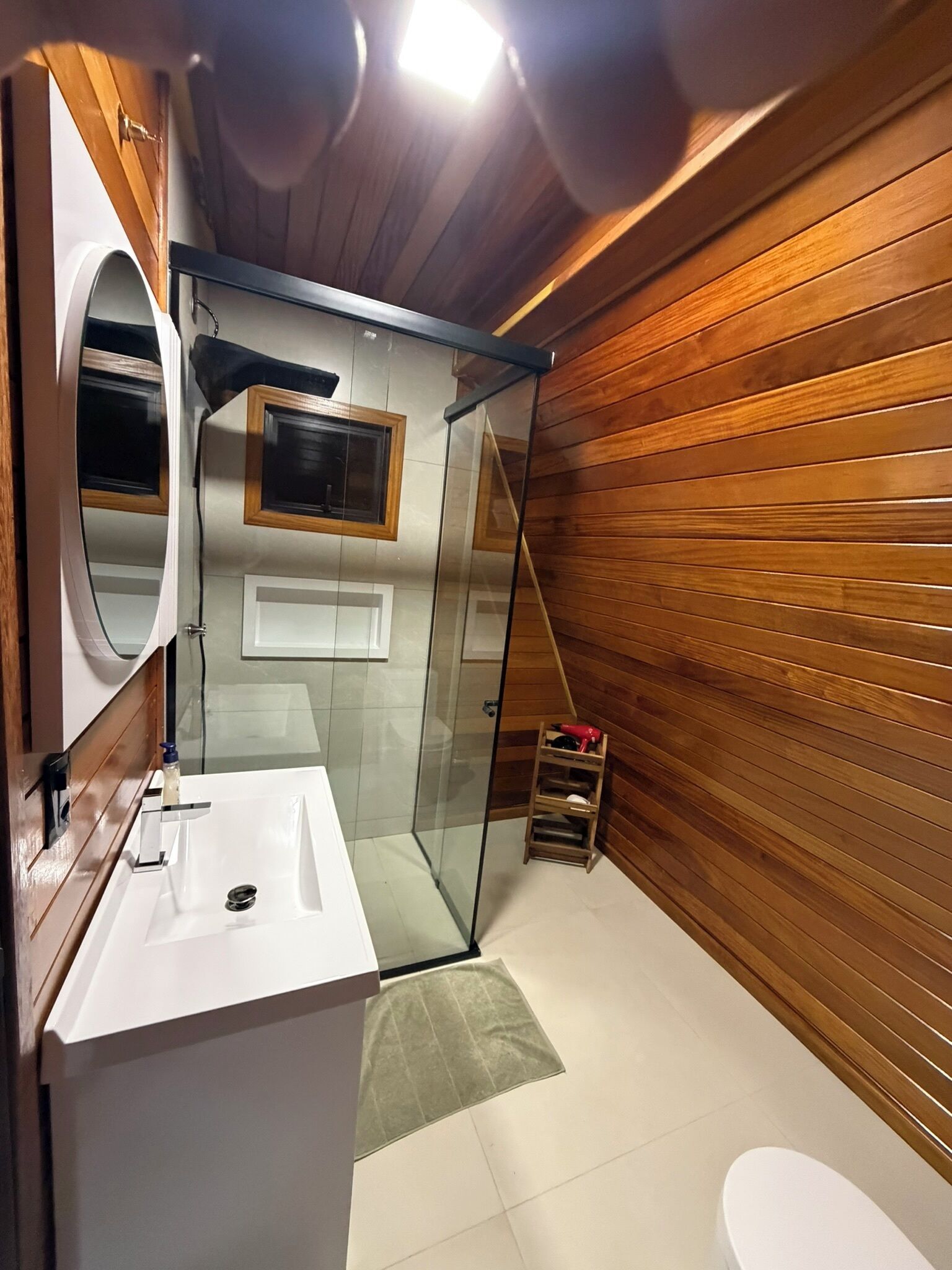 Un baño con lavamanos blanco, espejo y cabina de ducha de vidrio.